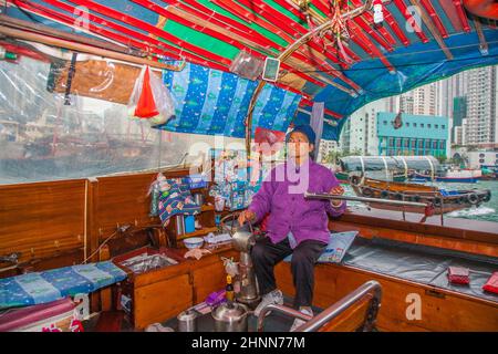 Im Hafen von Aberdeen, Hongkong, bietet die alte Frau ihr Boot für Taxifahrten an Stockfoto