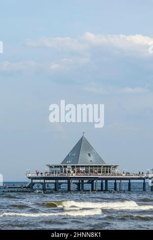 Die Menschen genießen Pier und Strand von Heringsdorf, Deutschland. Die Geschäfte am Pier bieten Essen und Kleidung an. Stockfoto