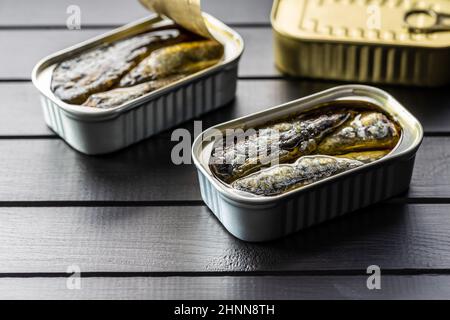 Sardinen aus der Dose. Seefisch in Zinndose auf schwarzem Tisch. Stockfoto