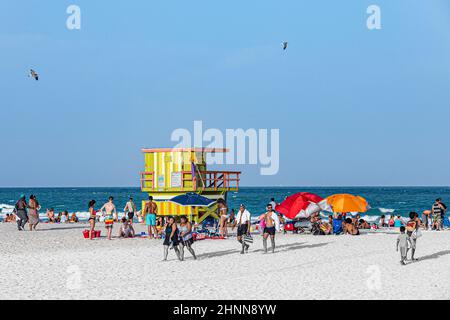 Die Menschen genießen South Beach in Miami Beach und sitzen vor dem farbenfrohen Rettungsschwimmerturm Stockfoto