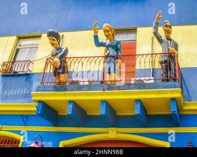 Statuen grüßen von einem Balkon aus die Touristen besuchen die Caminito Straße, Buenos Aires, Argentinien. Caminito ist eine traditionelle Gasse, die sich in La Boca befindet Stockfoto