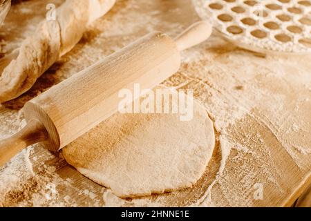 Hausgemachter Knödelteig. Das Nudelholz rollt Teig, Mehl und eine Form für Knödel oder Ravioli aus. Hausgemachte Speisen. Nationale Küche. Stockfoto