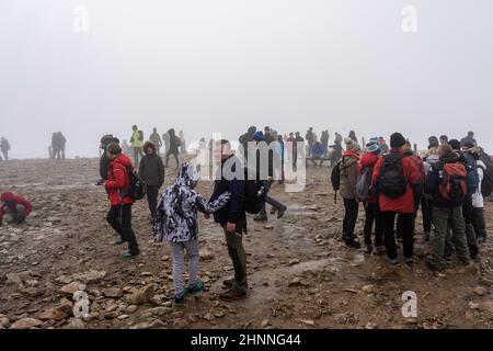 KARPACZ, POLEN - 16. OKTOBER 2021: Touristen auf dem Gipfel von Sniezka im Riesengebirge bei bewölktem Wetter. Stockfoto