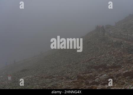 KARPACZ, POLEN - 16. OKTOBER 2021: Touristen besteigen den beliebten polnischen Berggipfel Sniezka im Riesengebirge bei bewölktem Wetter. Stockfoto