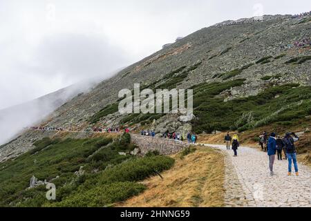 KARPACZ, POLEN - 16. OKTOBER 2021: Touristen besteigen den beliebten polnischen Berggipfel Sniezka im Riesengebirge bei bewölktem Wetter. Stockfoto