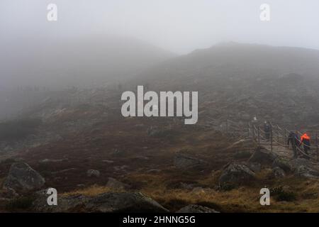 KARPACZ, POLEN - 16. OKTOBER 2021: Touristen besteigen den beliebten polnischen Berggipfel Sniezka im Riesengebirge bei bewölktem Wetter. Stockfoto