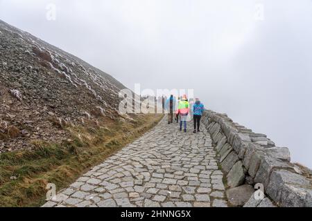 KARPACZ, POLEN - 16. OKTOBER 2021: Touristen besteigen den beliebten polnischen Berggipfel Sniezka im Riesengebirge bei bewölktem Wetter. Stockfoto