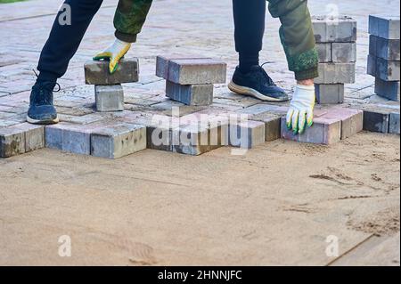 Pflasterplatten mit den Händen auf den Sand legen Stockfoto