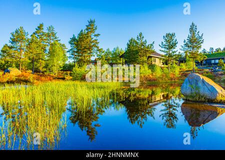 Morgenaufgang mit Spiegelung im Seenfluss in der Naturlandschaft Norwegens in Treungen Urlaubsresort in Nissedal Norwegen. Stockfoto