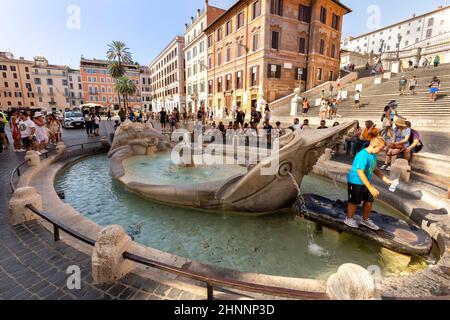 Die Menschen genießen die spanische Treppe auf der Piazza di Spagna in Rom. Spanische Treppe mit dem Brunnen Barcaccia in Rom ist ein berühmtes Touristenziel Stockfoto