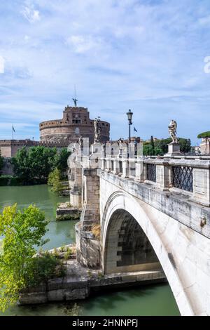 Die Menschen genießen es, das Schloss des heiligen Engels in Rom zu besuchen, indem sie den Fluss Tiber an der Brücke der heiligen Engel in Rom, Italien, überqueren. Stockfoto