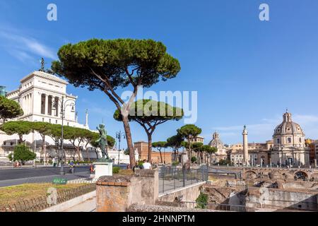 Menschen, die auf der Via Dei Fori Imperiali Street spazieren. Denkmäler der Göttin Victoria, die auf Quadriga auf dem Alter des Vaterlandes Gebäude im Hintergrund reitet Stockfoto