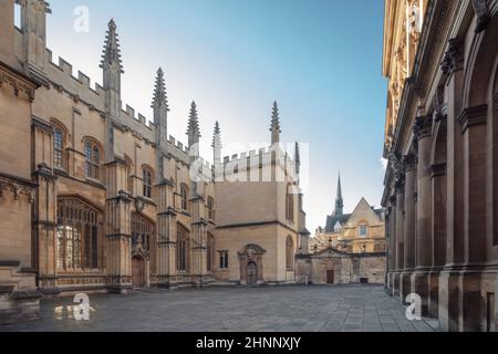 Großbritannien, Oxford University. Nordfassade der mittelalterlichen gotischen Göttlichkeitsschule mit dem Sheldonian Theater (vorne rechts), keine Menschen, sonniger Tag. Stockfoto