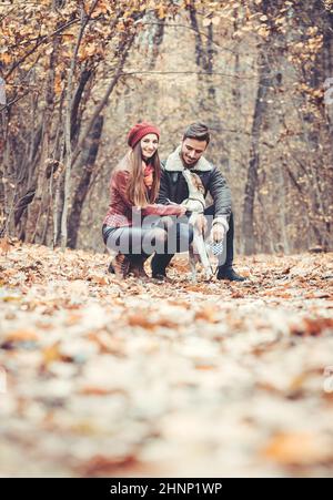 Frau und Mann streicheln den Hund zu Fuß sie in einem bunten Herbst Einstellung Spaß in der Natur Stockfoto