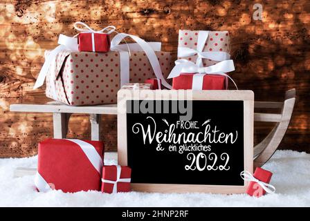 Tafel mit deutscher Kalligraphie Frohe Weihnachten und ein glückliches 2022 bedeutet Frohe Weihnachten und Ein glückliches 2022. Schlitten Mit Weihnachtsgeschenk Und Pr Stockfoto