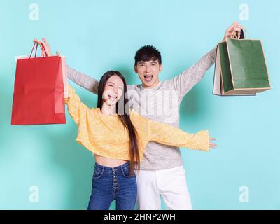Aufgeregt junges Paar mit Einkaufstaschen.isoliert auf blauem Hintergrund. Stockfoto