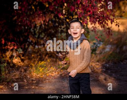 Hübscher stilvoller Junge, der im Herbstpark steht. Stil, Mode. Stockfoto