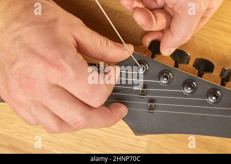 Neue Saite auf eine E-Gitarre setzen, Saitenwechsel und Tuning Stockfoto