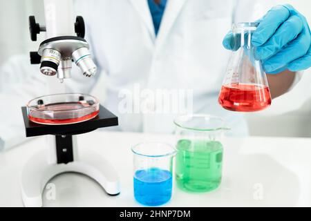 Asian Wissenschaftler Biochemiker oder Mikrobiologe arbeiten Forschung mit einem Mikroskop im Labor. Zum Schutz vor Ausbruch Coronavirus Covid19, Bakterien und Keimen. Stockfoto