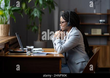 Freundliche afro Frau Remote Callcenter-Mitarbeiter in Headset mit Mikrofon kommunizieren mit Kunden Stockfoto