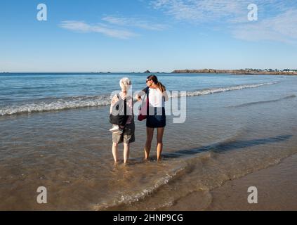 Zwei Frauen laufen an einem sonnigen Tag am Strand in Saint-Malo, Bretagne, Frankreich Stockfoto