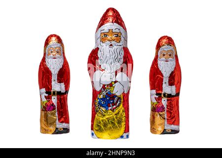 SchokoladenSanta isoliert. Nahaufnahme von drei fröhlich eingewickelten Schokoladen-Weihnachtsmann oder der guten Nikolaus-Figur auf weißem Hintergrund. Makrofotografie. Stockfoto