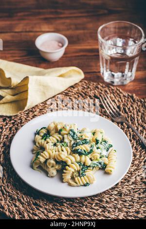 Cremige Pasta mit Spinat und Thymian auf weißem Teller Stockfoto