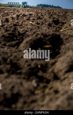 Traktor, der auf dem Bauernhof arbeitet, moderner Landtransport, Landwirt, der auf dem Feld arbeitet, Traktor auf dem Hintergrund des Sonnenuntergangs, Anbau von Land, landwirtschaftliche Maschine Stockfoto