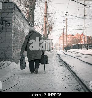 17th. November 2021, Russland, Tomsk, alte Frau gehen auf dem Rialway mit Taschen Stockfoto