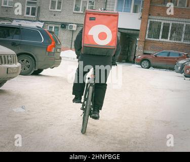 17th. November 2021, Russland, Tomsk, Fahrradkurier im Winter auf der Straße Stockfoto