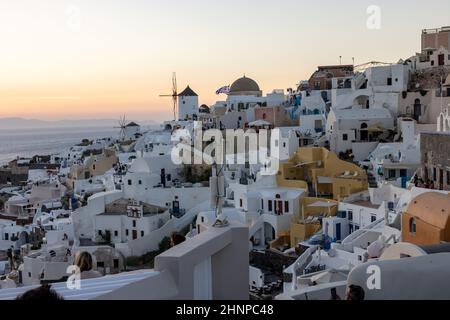 Weiß getünchte Häuser und Windmühlen in Oia in warmen Sonnenstrahlen auf Santorini. Griechenland Stockfoto
