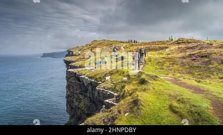 Eine Gruppe von Touristen, die wandern und die berühmten Cliffs of Moher, Irland, besichtigen Stockfoto