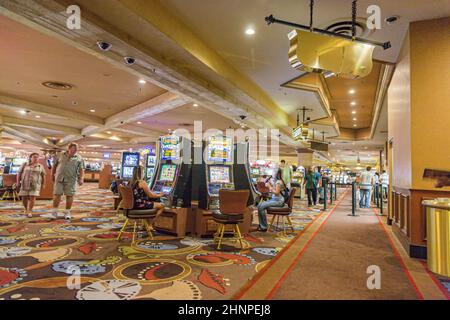 Spieler, die im Casino sitzen und mit Spielautomaten spielen Stockfoto