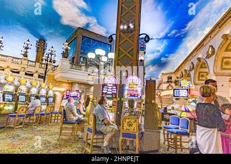 Spieler, die im Casino sitzen und mit Spielautomaten spielen Stockfoto