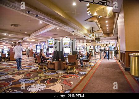Spieler, die im Casino sitzen und mit Spielautomaten spielen Stockfoto