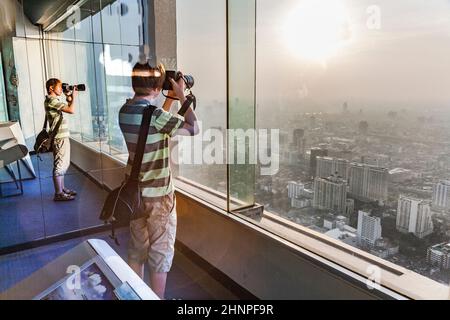 Die Menschen genießen den Blick auf die Skyline von Bangkok von der Plattform am Aussichtspunkt Mahanakhon Skywalk Stockfoto