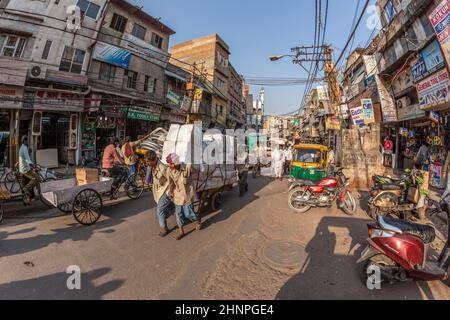 Der Mensch trägt schwere Ladung mit seinem Holzkarren im alten Delhi Stockfoto