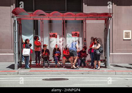 In der Mittagshitze warten die Leute an einer Bushaltestelle auf den nächsten Bus Stockfoto