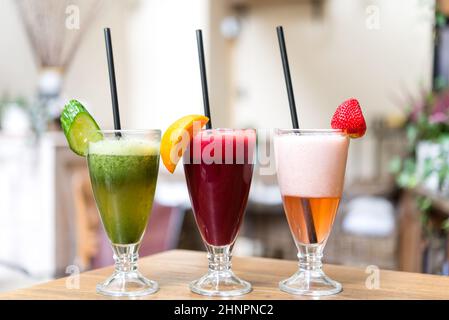 Drei Gläser von frischem Obst und Gemüse-Smoothies in einer Reihe auf Holztisch angeordnet Stockfoto