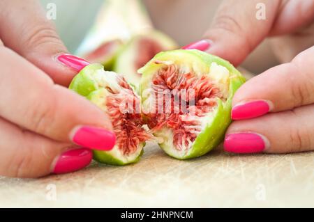 Frische Feigen, die mit weiblichen Fingern in zwei Stücke gerissen wurden Stockfoto