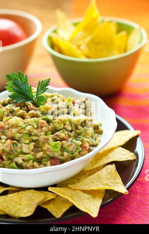 Guacamole-Salat in Schüssel weiß mit Petersilie obenauf angeordnet Stockfoto