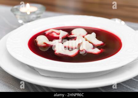 Traditionelle polnische rote Borschtsch-Suppe mit Knödeln auf weißen Teller. Sehr flach Dept Feld Stockfoto