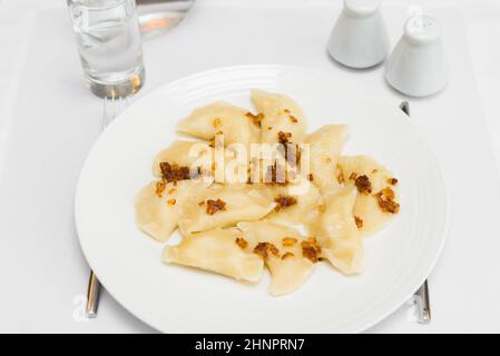 Leckere hausgemachte Knödel mit gebratenen Zwiebeln, angeordnet auf weißen Teller Stockfoto