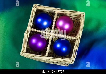 Christbaumkugeln in Korb auf blauen und grünen Hintergrund angeordnet Stockfoto