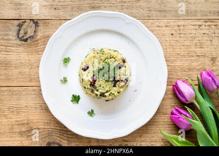 Draufsicht der Risotto (Pilaw) mit Jasmin-Reis, roten Bohnen und Gemüse auf weißen Teller auf rustikalen Holztisch Stockfoto