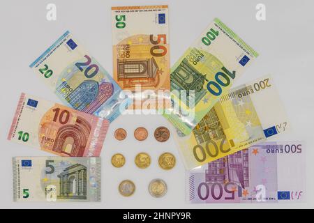 Jede Art von Euro-Münzen im Zentrum und Banknoten wurden wie ein Bogen auf weißem Hintergrund entsorgt Stockfoto