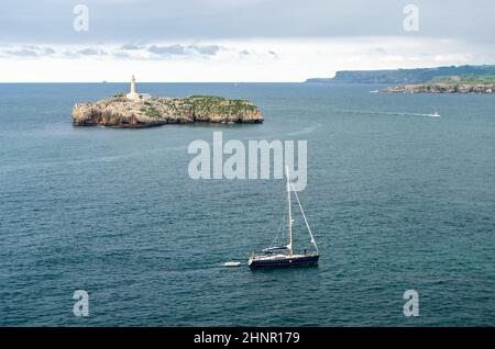 SANTANDER, SPANIEN - 9. JULI 2021: Blick von der Halbinsel Magdalena, Santander, Spanien, mit einem kleinen Boot, das segelt, und die Mouro-Insel im Hintergrund mit ihrem Leuchtturm aus dem 19th. Jahrhundert Stockfoto