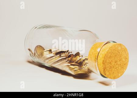 Glasbecher mit Korkstopfen und gefüllt mit internationalen Münzen aus verschiedenen Ländern. Transparente Moneybox. Finanzspeicherkonzept Stockfoto