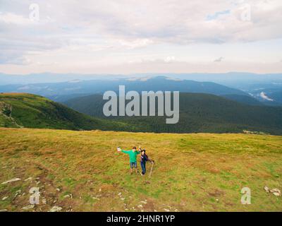 Luftaufnahme des Great Green Ridge. Guy und Girl stehen auf einem großen Hügel vor dem Hintergrund einer riesigen Berglandschaft Stockfoto