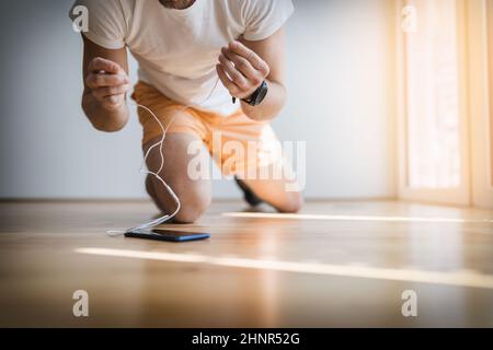 Hübscher junger Mann, der zu Hause mit einem intelligenten arbeitet Sehen Sie Stockfoto